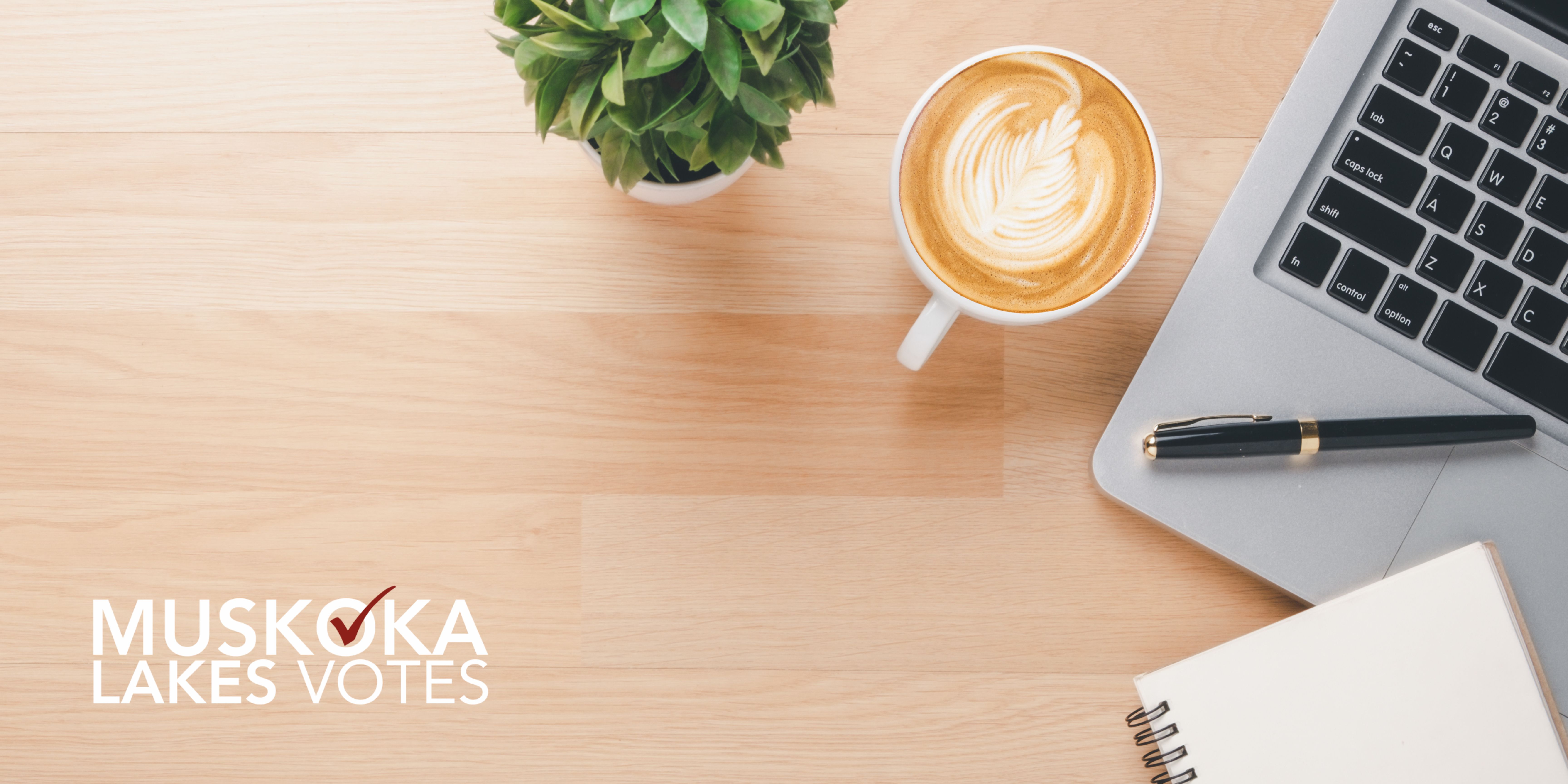 aerial view of a desk and laptop, with the Muskoka Lakes Votes logo