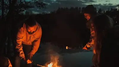 three people around a campfire