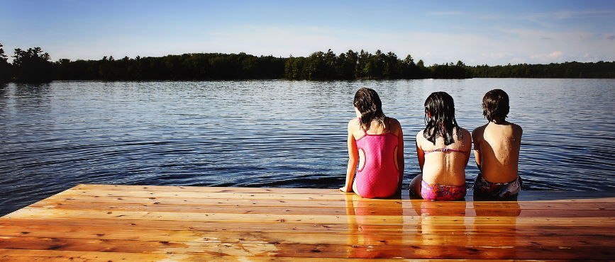 Kids in wet swimsuits sitting on a dock