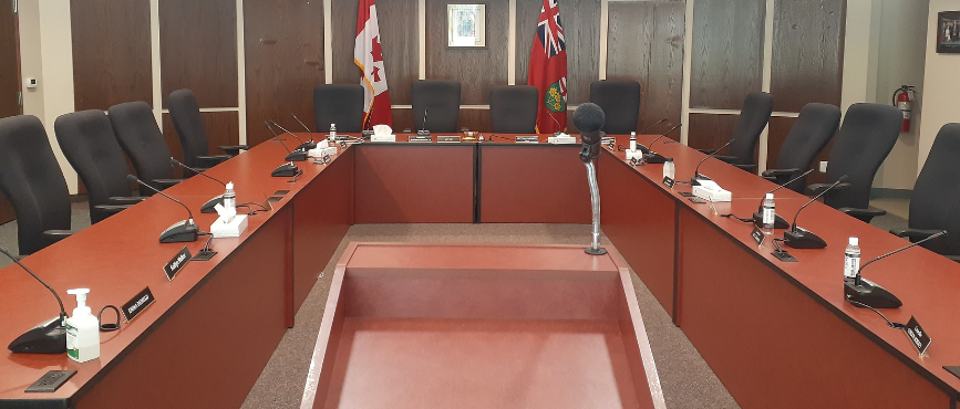 Interior of Council Chambers with a microphone and podium set up in front of Council's table